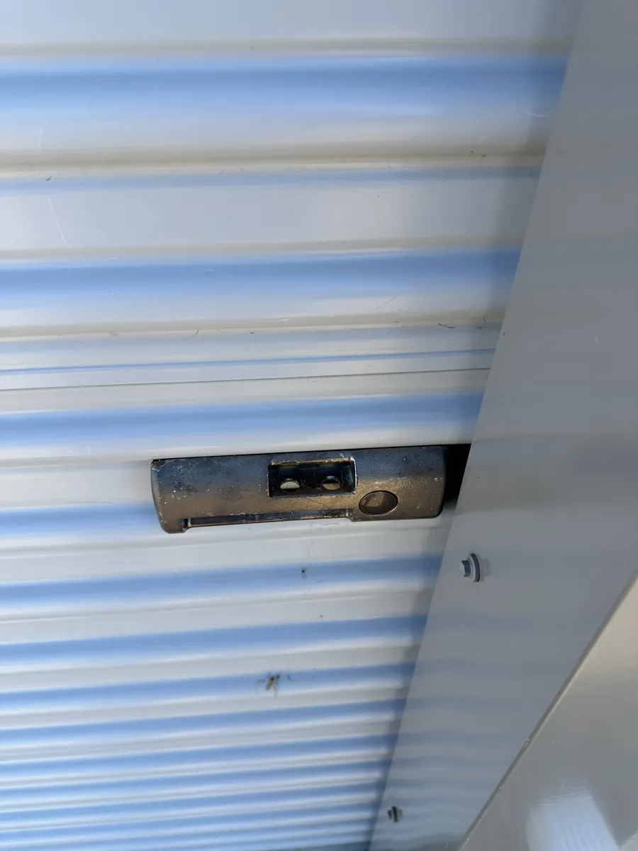 Close-up of the latch on a white roll-up bay door, where the renter's lock goes